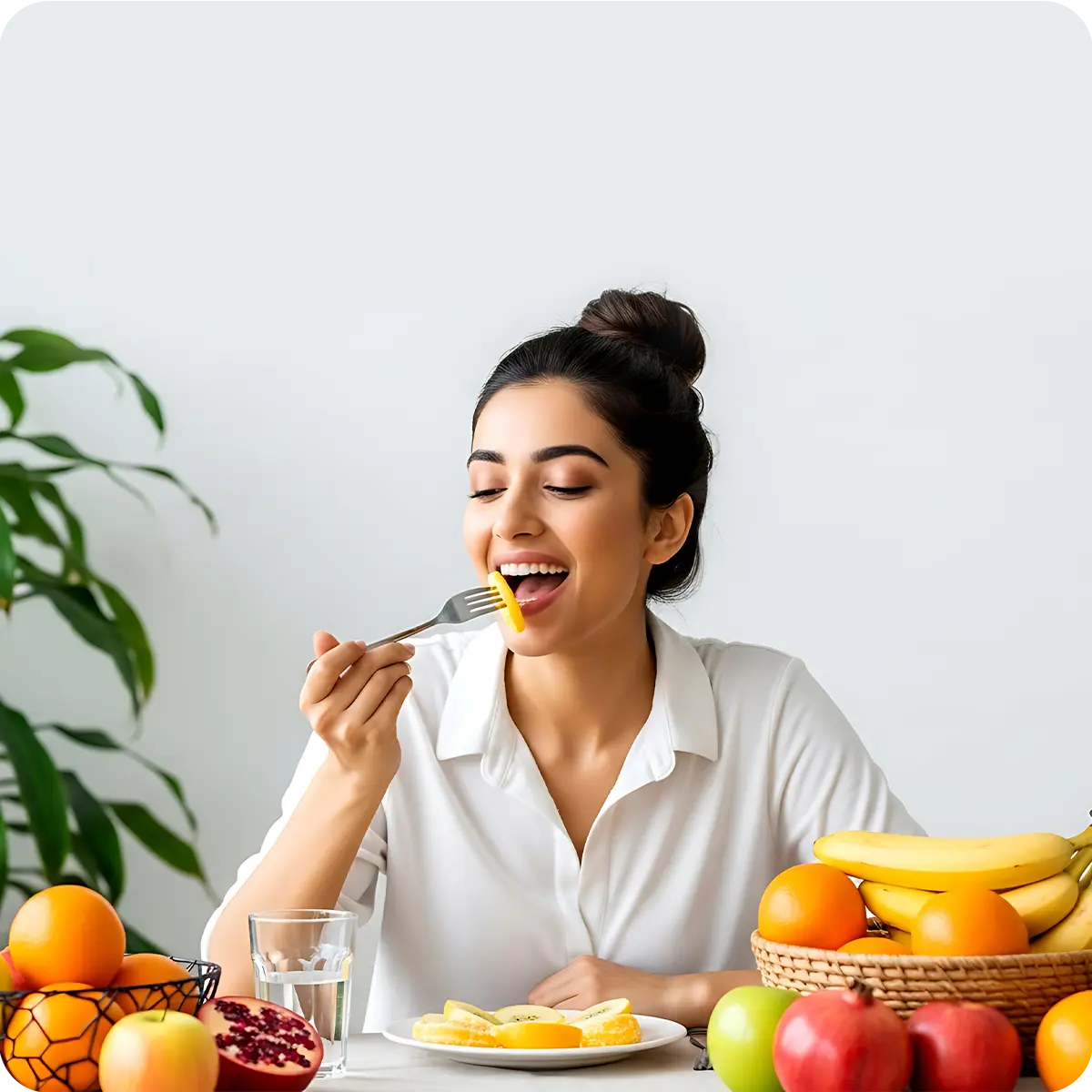 Photo of a woman happily eating a piece of fruit at a table surrounded by healthy foods, symbolizing the support for the effective utilization of essential nutrients and vitality.