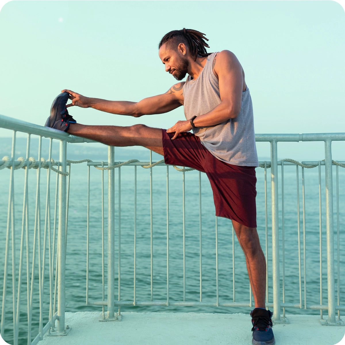 Image of an athlete stretching his leg outdoors by the water, illustrating the benefit: Helps Manage Muscle Activity & Recovery. Magnesium supports proper muscle contraction and relaxation, while Zinc helps in tissue repair